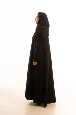 Attention to appearance, the concept of femininity and elegance, a side portrait of a smiling Saudi Gulf Arab woman wearing a hijab and an abaya, looking at the camera with expressions of joy, standing upright and ready, full-body image, white background.