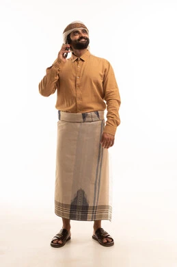 اجراء مكالمة هاتفية عبر الهاتف المحمول، مفهوم التقنيات والأجهزة الحديثة، بورتريه لرجل عربي يمني يرتدي القميص والازار مع العمامة يحمل بيده الجوال، صورة الجسم بالطول الكامل، خلفية بيضاء