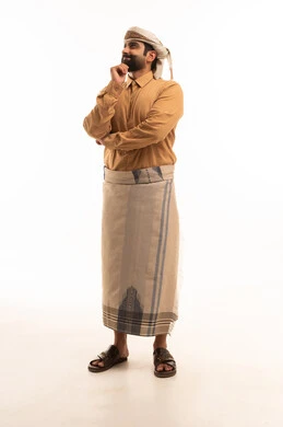 Contemplation and planning for the future, focus and distraction of the mind and reflection, finding a solution to a problem, a portrait of an Arab Yemeni man wearing a shirt and a waist wrap with a turban, resting his hand on his chin and looking at something with gestures of thought, full-body image, white background.