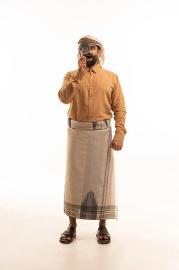 ايماءات وجه تدل على الدهشة، حب الاستكشاف والمغامرة, بورتريه لرجل عربي يمني يرتدي القميص والازار مع العمامة يحمل بيده عدسة مكبرة ينظر من خلالها, أدوات بصرية للرؤية عن قرب، مشاهدة الاشياء الصغيرة بدقة ووضوح, الجسم بالطول الكامل، خلفية بيضاء