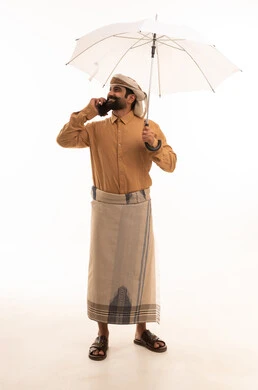 اجراء مكالمة هاتفية عبر الهاتف المحمول، بورتريه لرجل عربي يمني يرتدي القميص والازار مع العمامة يحمل بيده مظلة، الحماية من الأمطار في الشتاء، الجسم بالطول الكامل، خلفية بيضاء