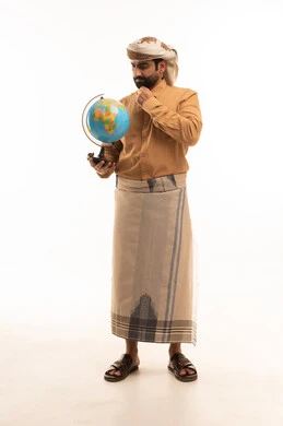 Daydreaming and thinking about a specific matter, going on exploratory tourist trips around the world, a portrait of an Arab Yemeni man wearing a shirt and a sarong holding a globe with gestures of confusion in pinpointing a location, a full-body image, white background.