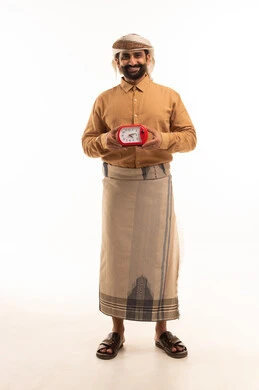 التذكيرات والتنبيهات الثابته ، الدقة في المواعيد، مفهوم إدارة وقت العمل، بورتريه لرجل عربي يمني يرتدي القميص والازار يحمل ساعة رقمية صغيرة ينظر الى الكاميرا بتعابير السرور، إنجاز المهام في الوقت، الجسم بالطول الكامل، خلفية بيضاء