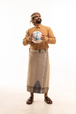 الشغف في متابعه الفرق وتشجيع المنتخبات، النظر الى شيء ما بايماءات السرور والسعادة، بورتريه لرجل عربي يمني يرتدي القميص والازار مع العمامة يحمل كرة قدم يقوم بمشاهدة المباريات، قضاء وقت ممتع في المنزل، خلفية بيضاء