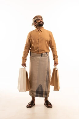 Looking at something, shopping and taking the necessary items, commercial purchases and gifts, benefiting from discounts and clearance sales, a portrait of an Arab Yemeni man wearing a shirt and a waist wrap with a turban holding colorful paper bags in his hand, full body, white background.
