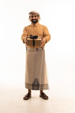 تقديم الهدايا بالاعياد والمناسبات الخاصة، مفهوم الشكر والامتنان، التعبير عن الحب والتقدير والاحترام، بورتريه لرجل عربي يمني يرتدي القميص والازار مع العمامة يحمل بيديه صندوق هدية ينظر بايماءات السعاده والسرور، الجسم بالطول الكامل، خلفية بيضاء
