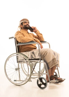 Making a phone call via mobile, communicating with family and friends, using modern technology and techniques, a portrait of an Arab Yemeni man wearing a shirt and a waist wrap with a turban sitting in a wheelchair holding a mobile phone, white background. Making a phone call via mobile, communicating with family and friends, using modern technology and techniques, a portrait of an Arab Yemeni man wearing a shirt and a waist wrap with a turban sitting in a wheelchair holding a mobile phone, white background.