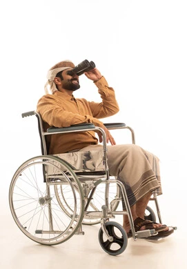 Gestures of enjoyment and pleasure, a love for exploration and adventure, seeing distant things and bringing them closer, a portrait of a Yemeni Arab man wearing a shirt and a sarong with a turban sitting in a wheelchair looking through binoculars, white background.