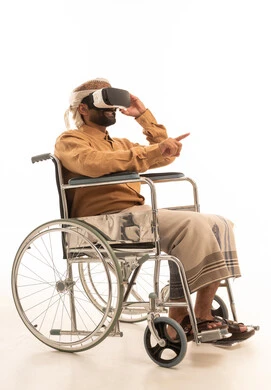 الاندماج ومحاكاة العالم الخيالي، الاشارة الى شيء ما، المتعة والتسلية بالمشاهدة عبر نظارة الواقع الافتراضي، بورتريه لرجل عربي يمني يرتدي القميص والازار مع العمامة يجلس على كرسي متحرك يضع نظارة ثلاثية الأبعاد (الفي ار), التطور التقني والتكنولوجي ، خلفية بيضاء