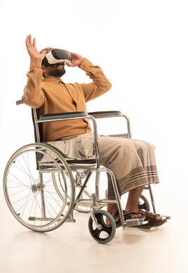 ارتداء نظارة الفي آر ثلاثية الأبعاد, التطور التقني والتكنولوجي,  بورتريه لرجل عربي يمني يرتدي القميص والازار مع العمامة يجلس على كرسي متحرك  ينظر من خلال نظارات الواقع الافتراضى, رفع كف اليد للأعلى بإيماءات الاندماج ومحاكاة العالم الخيالي، خلفية بيضاء