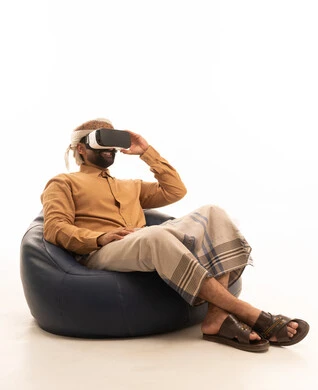 تجربة العالم الخيالي التفاعلي، التطور التقني والتكنولوجي، المتعة والتسلية بالمشاهدة عبر نظارة الواقع الافتراضي، بورتريه لرجل عربي يمني يرتدي القميص والازار مع العمامة يجلس على كرسي بين باج يضع نظارة ثلاثية الأبعاد (الفي ار)، خلفية بيضاء