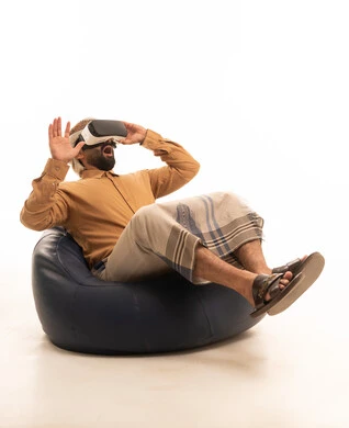 الاندماج ومحاكاة العالم الخيالي، المتعة والتسلية بالمشاهدة عبر نظارة الواقع الافتراضي، بورتريه لرجل عربي يمني يرتدي القميص والازار مع العمامة يجلس على كرسي بين باج يضع نظارة ثلاثية الأبعاد (الفي ار), التطور التقني والتكنولوجي، خلفية بيضاء