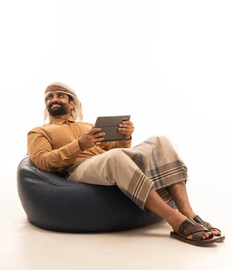 النظر الى شيء ما، استعمال التكنولوجيا والتقنية الحديثة, تصفح مواقع التواصل الاجتماعي عبر الجهاز اللوحي، المحادثة مع الأهل والأصدقاء، بورتريه لرجل عربي يمني يرتدي القميص والازار مع العمامة يجلس على كرسي بين باج يحمل بيده جهاز التابلت، خلفية بيضاء النظر الى شيء ما، استعمال التكنولوجيا والتقنية الحديثة, تصفح مواقع التواصل الاجتماعي عبر الجهاز اللوحي، المحادثة مع الأهل والأصدقاء، بورتريه لرجل عربي يمني يرتدي القميص والازار مع العمامة يجلس على كرسي بين باج يحمل بيده جهاز التابلت، خلفية بيضاء