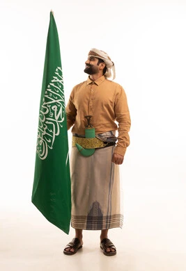 إحياء ذكرى اليوم الوطني السعودي 23 سبتمبر، يوم العلم السعودي 11 مارس, إيماءات الفخر و السرور بالانتماء للوطن, بورتريه لرجل عربي يمني يرتدي القميص والازار مع العمامة والجنبية يحمل بيده علم المملكة، يوم بدينا 1727 م، الجسم بالطول الكامل، خلفية بيضاء