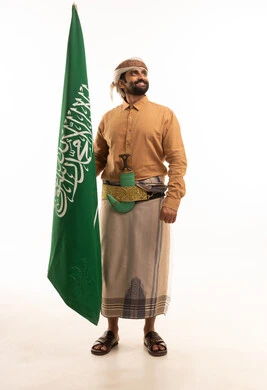 يوم العلم السعودي 11 مارس، إحياء ذكرى اليوم الوطني السعودي 23 سبتمبر, إيماءات الفخر و السرور بالانتماء للوطن, بورتريه لرجل عربي يمني يرتدي القميص والازار مع العمامة والجنبية يحمل بيده علم المملكة، يوم بدينا 1727 م، الجسم بالطول الكامل، خلفية بيضاء