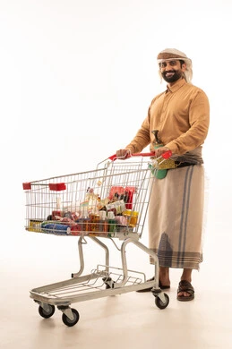 Looking at the camera with expressions of pleasure, buying necessities and essentials, enjoying shopping in malls and shopping centers, taking advantage of discounts and sales on products, and a portrait of a Yemeni Arab man wearing a shirt and izar with a turban and jambiya, holding a shopping cart, white background.
