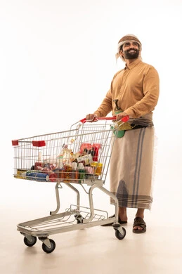 النظر الى شيء ما، شراء المستلزمات والحاجيات الضرورية، الاستمتاع بالتسوق في المولات والمراكز التجارية، الاستفادة من الخصومات والتنزيلات على المنتجات، بورتريه لرجل عربي يمني يرتدي القميص والازار مع العمامة والجنبية يمسك بيدية عربة التسوق، خلفية بيضاء