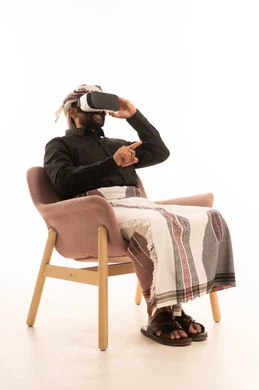 إيماءات الاندماج ومحاكاة العالم الخيالي, التطور التقني والتكنولوجي, ارتداء نظارة الفي آر ثلاثية الأبعاد ,بورتريه لرجل عربي يمني يرتدي القميص والازار مع العمامة يجلس على كرسي ينظر من خلال نظارات الواقع الافتراضى، خلفية بيضاء