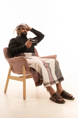 إيماءات الخسارة وخيبة الأمل، استخدام الألعاب الإلكترونية والأجهزة الحديثة، بورتريه لرجل عربي يمني يرتدي القميص والازار مع العمامة يجلس على كرسي يمسك عصا التحكم يضع يده على رأسه بتعابير الحسرة والحزن، التسلية والترفيه بالفيديو جيمز في وقت الفراغ، خلفية بيضاء