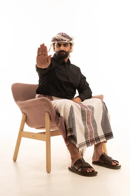 تعابير الرفض والإمتناع، الأمر بالتوقف عن فعل شيء ما، بورتريه لرجل عربي يمني يرتدي القميص والازار مع العمامة يجلس على كرسي يرفع يدية بإيماءات تدل على النهي، الشعور بالإنزعاج والغضب، خلفية بيضاء