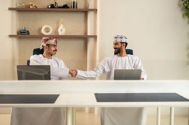 الاستعانة بالأجهزة التقنية الحديثة، إتمام المهام في المكتب، تطور الشركات العمانية , العمل الجماعي و التعاون، موظفان عربيان خليجيان عمانيان يرتديان الدشداشة والكمة عمانيان ويقومان باستخدام اللابتوب و التابلت, الجلوس على كرسي مريح