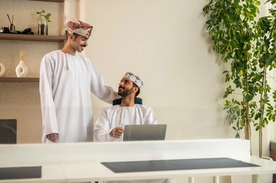 Completion of office work, the concept of project management, a clear explanation of tasks, discussion and dialogue in an office environment, division of tasks among employees, monitoring daily tasks, developing plans and achieving the company's goals, an Arab Gulf Omani team sitting at a desk using a laptop.