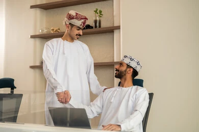 التعامل اللين بين الموظفين  , نقاش و حوار في بيئة مكتبية, تقسيم المهام والاعمال , متابعة المهام اليومية، إنجاز الأعمال المكتبية، مفهوم ادارة المشاريع، تطوير الخطط وتحقيق أهداف الشركة، فريق عمل عربي خليجي عماني يجلسون على مكتب يستخدمون الحاسوب المحمول