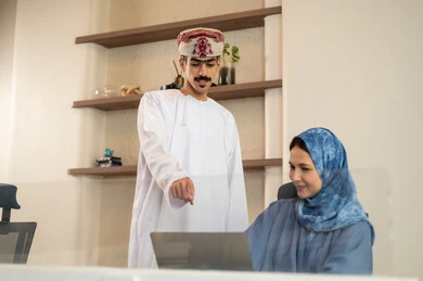 Discussion and dialogue in an office environment, division of tasks among employees, clear explanation of tasks, follow-up on daily tasks, completion of office work, concept of project management, developing plans and achieving company goals, an Arab Gulf Omani team sitting at a desk using a laptop. Discussion and dialogue in an office environment, division of tasks among employees, clear explanation of tasks, follow-up on daily tasks, completion of office work, concept of project management, developing plans and achieving company goals, an Arab Gulf Omani team sitting at a desk using a laptop.