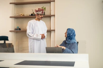 تقسيم المهام بين الموظفين, متابعة المهام اليومية، شرح واضح للتاسكات , نقاش و حوار في بيئة مكتبية,إنجاز الأعمال المكتبية، مفهوم ادارة المشاريع، تطوير الخطط وتحقيق أهداف الشركة، فريق عمل عربي خليجي عماني يجلسون على مكتب يستخدمون الحاسوب المحمول