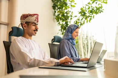 متابعة المهام اليومية، إنجاز الأعمال المكتبية، شرح واضح للتاسكات , نقاش و حوار في بيئة مكتبية, تقسيم المهام بين الموظفين, مفهوم ادارة المشاريع، تطوير الخطط وتحقيق أهداف الشركة، فريق عمل عربي خليجي عماني يجلسون على مكتب يستخدمون الحاسوب المحمول