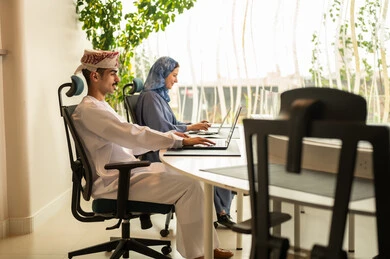 مفهوم ادارة المشاريع، تطوير الخطط وتحقيق أهداف الشركة، شرح واضح للتاسكات , نقاش و حوار في بيئة مكتبية, تقسيم المهام بين الموظفين, متابعة المهام اليومية، إنجاز الأعمال المكتبية، فريق عمل عربي خليجي عماني يجلسون على مكتب يستخدمون الحاسوب المحمول