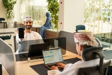 دمج التقنيات المتطورة فى العمل ،التعاون و متابعة الاعمال,  نمط الحياة في الشركات العمانية، تدريب الموظفين على سياسات العمل لتحقيق الأهداف في المكتب داخل مقر الشركة،فريق عربي خليجي عماني مكون من رجلان يرتديان الدشداشة والكمة  وسيدة محجبة ترتدي العباءة الزرقاء , انجاز المهام من خلال اللابتوب و التابلت والهاتف المحمول