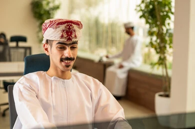 دمج التقنيات المتطورة فى العمل ،التعاون و متابعة الاعمال, نمط الحياة في الشركات العمانية ، تدريب الموظفين على سياسات العمل لتحقيق الأهداف في المكتب داخل مقر الشركة، فريق عربي خليجي عماني مكون من رجلين يرتديان الدشداشة والكمة , انجاز المهام من خلال اللابتوب و التابلت