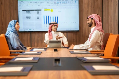 إدارة و تقسيم المهام، فريق عمل عربي خليجي سعودي يقوم بإجراء اجتماع عمل داخل غرفة الاجتماعات في مقر الشركة، شرح و تحليل الرسوم البيانية, دمج الأجهزة التقنية الحديثة بالأعمال المكتبية، دراسة أوراق البيانات الإحصائية, تطوير المشاريع و الاستثمارات