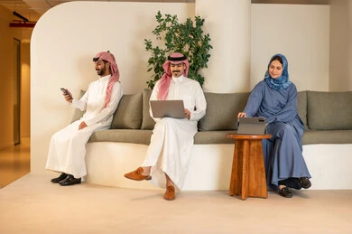 Following the work strategy, understanding and cooperation among colleagues to achieve the company's goals, the concept of business management, completing tasks using modern devices, Arab Gulf Saudi colleagues sitting in the office working on laptops and tablets, discussing ideas and exchanging opinions.