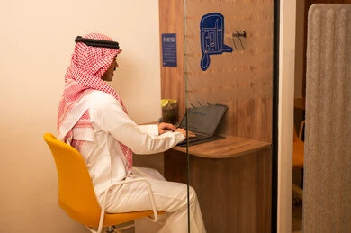 دمج التقنيات الحديثة و المتطورة مع العمل, مهن و أعمال مكتبية إدارية, رجل عربي خليجي سعودي  يرتدي الزي التقليدي والشماغ يجلس على المكتب امام جهاز اللابتوب و يتحدث عبر المحمول,  التواصل مع العملاء عن بعد، ارسال بريد إلكتروني عبر الكمبيوتر،تعابير وايماءات الاندماج