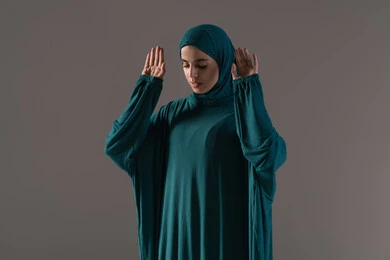 الإعداد البدني والروحي للصلاة، أداء الفرائض بأوقاتها، مفهوم أركان الإسلام،  بورتريه لإمرأة عربية خليجية سعودية ترتدي الحجاب والعباءة تقف على السجادة، العبادة والتقرب إلى الله، الركوع والسجود والخشوع، خلفية رمادية