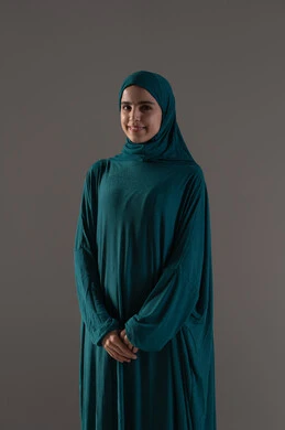 A beautiful young Muslim woman, the concept of commitment to religion, a portrait of a Saudi Gulf Arab woman wearing a hijab and abaya, standing upright looking at the camera with gestures of reassurance and contentment, expressions of happiness and joy, worship and closeness to God Almighty, gray background.