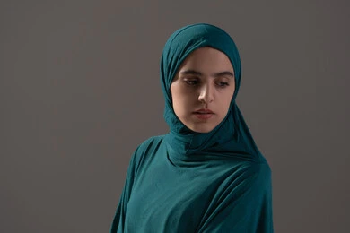 إقامة الصلاة على وقتها، أداء الفرائض الدينية الإسلامية, مفهوم أركان الإسلام، بورترية لامراه عربيه خليجيه سعودية تقوم بالتسليم في ختام الصلاة، الشعور بالخشوع والطمأنينة، العبادة والتقرب إلى الله، خلفية رمادية