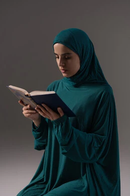الانتباه الروحي والتدبر أثناء العبادة، التقرب الى الله تعالى، بورترية لامراة عربيه خليجه عربيه سعودية ترتدي العباءة و الحجاب تقرأ القرآن الكريم، المناسبات الدينية والأعياد الإسلامية، خلفيه رمادية