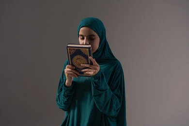التقدير والاحترام للمصحف الشريف، الاجتهاد في العباده والطاعة، ، حب كتاب الله و تقبيله, بورترية لامراة عربيه خليجه عربيه سعودية ترتدي العباءة و الحجاب تمسك القرآن الكريم بيديها، خلفية رمادية