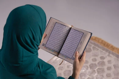 التركيز والوقار أثناء أداء العبادات، التقرب الى الله تعالى، بورترية مقرب من الخلف لامراة عربيه خليجه عربيه سعودية ترتدي العباءة و الحجاب تقرأ القرآن الكريم، المناسبات الدينية والأعياد الإسلامية، خلفيه رمادية