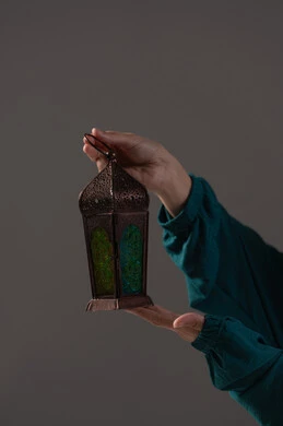 التحضير لاستقبال الشهر الكريم، بورترية مقرب ليدين امرأه عربيه خليجه عربيه سعودية تحمل بيدها فانوس رمضان الملون, ديكورات شهر رمضان المبارك، خلفية رمادية