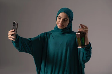Worship and drawing closer to God, enjoying the spiritual atmosphere in the blessed month of Ramadan, a portrait of a Saudi Arabian Gulf woman wearing a hijab and abaya holding a mobile phone taking a picture of a metal lantern, gestures of happiness and joy, gray background. Worship and drawing closer to God, enjoying the spiritual atmosphere in the blessed month of Ramadan, a portrait of a Saudi Arabian Gulf woman wearing a hijab and abaya holding a mobile phone taking a picture of a metal lantern, gestures of happiness and joy, gray background.
