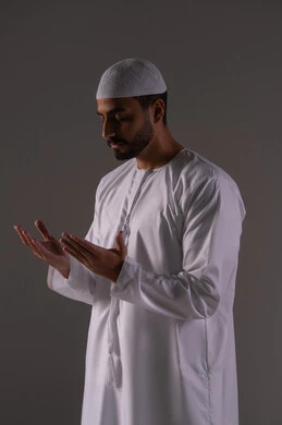 Turning to prayer and the desire to attain one's wishes, supplication to God Almighty, a portrait of an Arab Gulf Emirati man wearing a kandura and a white cap, raising his hands in humility and pleading, standing with gestures of prayer, supplication, and seeking mercy, asking with entreaty and humility from the Lord of the servants, white background.
