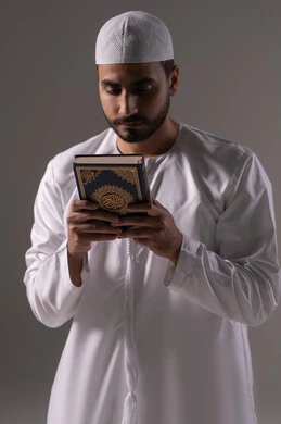 المواظبة على الطاعة والتعبد، تلاوة وقراءة القرآن الكريم وتدبر معانيه، بورتريه لرجل عربي خليجي إماراتي يرتدي الكندورة والقبعة البيضاء يحمل بيده المصحف الشريف، الإكثار من ذكر الله تعالى، التقرب الى الله في شهر رمضان، الشعور بالخشوع والطمأنينة، خلفية بيضاء