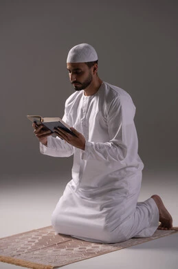التمتع بلحظات السكون والخشوع، فهم معاني القرآن والتعمق في تدبره، بورتريه لرجل عربي خليجي إماراتي يرتدي الكندورة والقبعة البيضاء يجلس على سجادة الصلاة  يقوم بقراءة المصحف الشريف، الإكثار من ذكر الله تعالى من خلال الاستغفار والدعاء، الاجتهاد في العبادة، التقرب الى الله في شهر رمضان، خلفية بيضاء