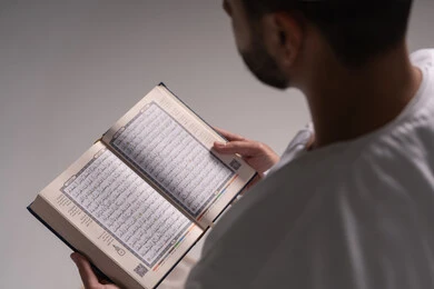 التفكر في آيات الذكر الحكيم، الشعور بالخشوع والطمأنينة، بورتريه  مقرب من الجانب لرجل عربي خليجي إماراتي يرتدي الكندورة يقوم بقراءة المصحف الشريف، الإكثار من ذكر الله تعالى من خلال الاستغفار والدعاء، الاجتهاد في العبادة، التقرب الى الله في شهر رمضان، خلفية بيضاء
