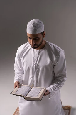 تدبر آيات القران الكريم، الشعور بالخشوع والطمأنينة، بورتريه لرجل عربي خليجي إماراتي يرتدي الكندورة والقبعة البيضاء يقوم بقراءة المصحف الشريف، الإكثار من ذكر الله تعالى من خلال الاستغفار والدعاء، الاجتهاد في العبادة، التقرب الى الله في شهر رمضان، خلفية بيضاء
