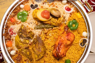 Preparing delicious and healthy recipes, dishes from traditional popular Arabic cuisine, a metal tray filled with rice and spices, a close-up image of a plate of rice garnished with stuffed chicken.